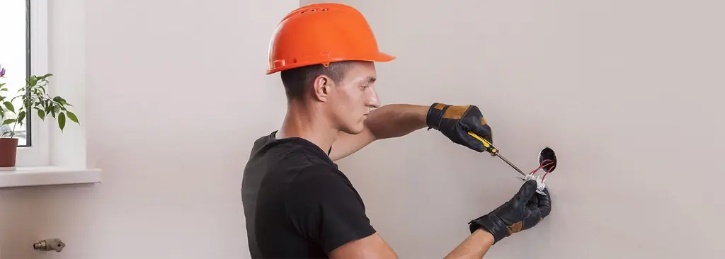 Electrician terminating a wall device on a commercial job